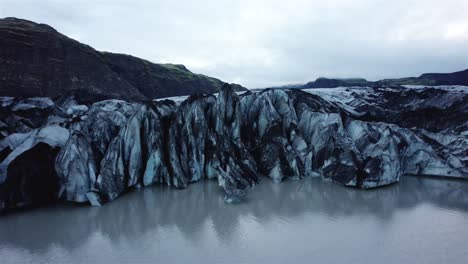 drone-shot-flying-sideways-and-upwards-in-front-of-Solheimajokull-Glacier,-Iceland-in-4k