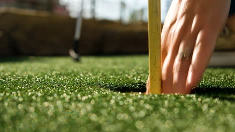 Lady-playing-miniature-golf-sinking-a-putt