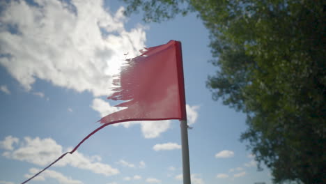 Bandera-Roja-Vieja,-Rota-Y-Andrajosa-Que-Fluye-En-El-Viento-En-Un-Día-Soleado