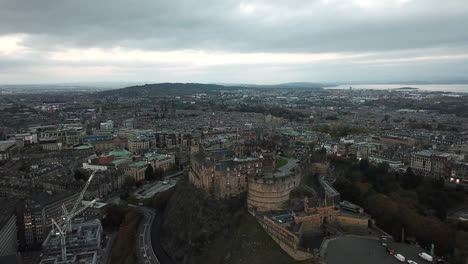 Impressive-drone-shot-high-above-Edinburgh-castle,-slowly-moving-towards-it-from-Arthur's-seat-and-finishing-looking-down-into-the-castle-courtyard