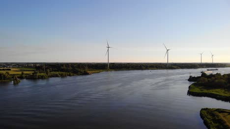 Aerial-Dolly-Forward-Over-Oude-Maas-With-Still-Wind-Turbines-And-Silhouette-Of-Ship-Approaching-In-Distance