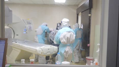 Medical-Staff-Wear-PPE-Move-Contagious-Patient-Out-Of-X-Ray-Machine-and-Disinfecting-The-Machine