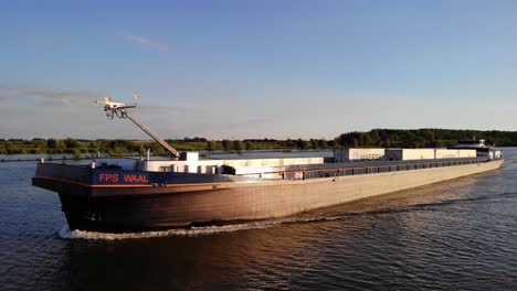 Aerial-Port-Side-View-Of-FPS-Waal-Inland-Cargo-Vessel-Along-Oude-Maas-With-During-Golden-Hour-Sunlight