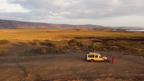 Eine-Atemberaubende-Drohnenaufnahme-Eines-Safari-Jeeps,-Der-Während-Der-Sonnenaufgangsstunden-Auf-Einem-Hügel-Mit-Blick-Auf-Den-Lake-Natron-In-Tansania-In-Afrika-Geparkt-Ist