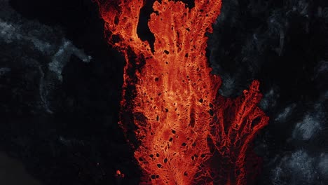 Large-flowing-river-of-molten-red-lava-in-rugged-volcanic-environment,-top-down