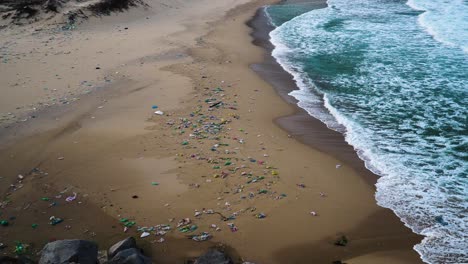Rubbish-thrown-by-sea-wave-on-tropical-beach-in-Vietnam,-pollution-concept
