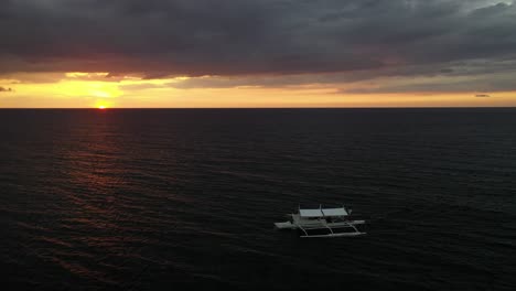 Ein-Einzelnes-Boot-Fährt-Langsam-Auf-Den-Friedlichen-Meereswellen-Im-Dramatischen-Sonnenuntergang,-Während-Dunkle,-Schwere-Wolken-Auf-Der-Insel-Cresta-De-Gallo-Auf-Den-Philippinen-Aufziehen