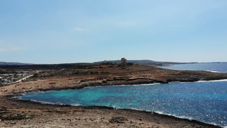 Vista-Aérea-Hacia-La-Playa-De-Coral,-Torre-Blanca-En-Mellieha-Armier-Bay,-Malta