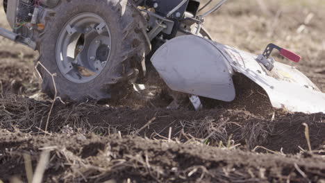 Rototiller-working-on-topsoil,-agriculture-in-Sweden,-slow-motion-close-up
