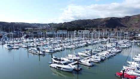 Luxury-yachts-and-sailboats-mooring-in-Conwy-Wales-colourful-sunny-mountain-marina-Aerial-view-left-orbit-slow