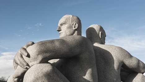 Granite-Statute-Of-Two-Men-Sitting-Back-To-Back-By-Gustav-Vigeland-As-Part-Of-Vigeland-Facility-At-Frogner-Park,-Oslo,-Norway