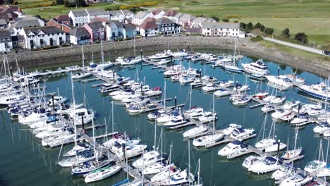 Flying-above-luxury-yachts-and-sailboats-reflections-on-sunny-Conwy-marina-birdseye-aerial-tilt-up-view