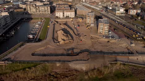 Backwards-aerial-view-revealing-a-construction-site-of-the-new-Kade-Zuid-luxury-apartment-building-project-in-Noorderhaven-neighbourhood-in-Hanseatic-city-Zutphen,-The-Netherlands