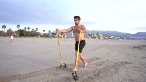 metabolic-training-on-the-beach-with-muscular-man-doing-chest-and-rubber-variant-with-kettlebell