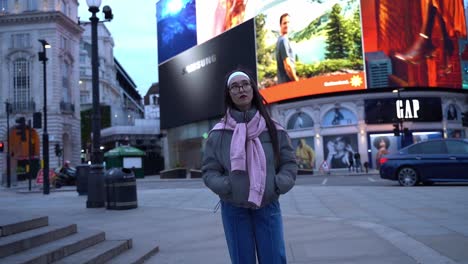 Young-woman-looks-around-in-Picadilly-Circus,-London,-UK,-wide-shot