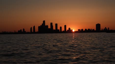 Static-shot-of-sunset-behind-skyline-silhouette-seen-from-beach