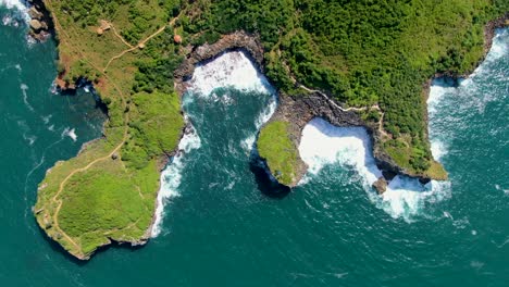 Top-view-on-ocean-wave-hit-Kesirat-coast-cliffs,-Java,-Indonesia,-aerial
