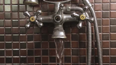 Male-Hand-Opening-and-Closing-Wall-Mounted-Double-Handle-Faucet-Close-up,-Hot-Water