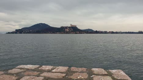 Running-over-Arona-jetty-with-Angera-castle-in-background,-Fpv-surface-level-pov