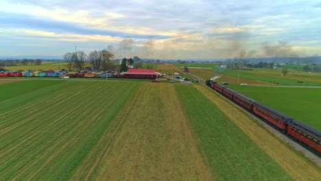 An-Aerial-View-of-an-Antique-Restored-Steam-Train-and-Passenger-Coaches-Following-With-Smoke-and-Steam-With-Tourists-and-Spectators-Watching-as-Seen-by-a-Drone