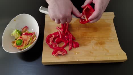 Slicing-a-red-bell-pepper-on-a-cutting-board,-medium-shot-overhead