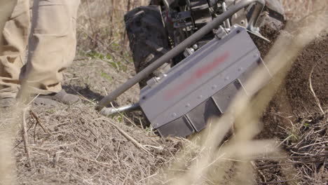 Rototiller-throws-topsoil-about,-agriculture-in-Sweden,-slow-motion-close-up