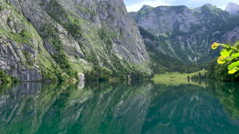 Water-reflection-of-idyllic-lake-surrounded-by-giant-mountains-in-summer,Austria---4K-tilt-down-shot