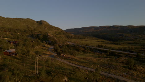 Aerial-flyover-natural-landscape-of-Hardangervidda-in-Norway-during-sunset---Idyllic-forest-trees-and-mountain-range