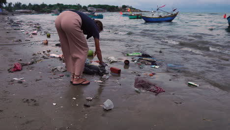 Eine-Frau-Sammelt-Umweltmüll-Vom-Strand-Voller-Plastik-Und-Trümmer-Entlang-Der-Küste-Ein