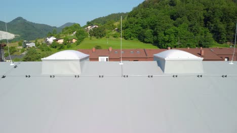 Flying-beside-rooftop-insulated-with-panels-with-light-cupola-domes-and-lightning-protection-poles-on-top