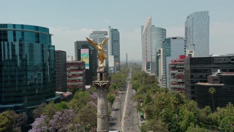 Aerial-of-monumento-a-la-independencia-landmark-in-mexico,-cyclists-in-background