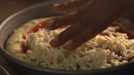 Von-Hand-Käse-Auf-Tomatenbasis-Auf-Pizzaboden-Streuen