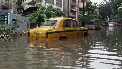 Yellow-taxi-vehicle-stuck-in-flooded-road-in-Kolkata,-India