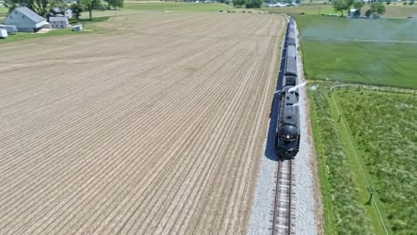 A-Drone-View-of-a-Steam-Locomotive-With-Passenger-Coaches-Approaching-over-Countryside-on-a-Beautiful-Summer-Day