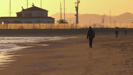 Gente-Caminando-En-La-Playa-De-Arena-En-Invierno,-Temprano-En-La-Mañana,-Costa-Mediterránea-De-España