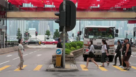 Kippaufnahmen-Von-Fußgängern,-Die-über-Einen-Zebrastreifen-Gehen,-Während-über-Ihnen-Hunderte-Von-Nationalflaggen-Chinas-Und-Der-SAR-Hongkong-Während-Des-Jubiläums-Der-Übergabe-Hongkongs-An-China-Zu-Sehen-Sind