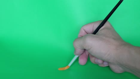 man-hand-drawing-line-with-paint-brush-on-green-background