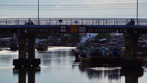 Phan-Thiet-bridge-with-small-boats-under-and-heavy-traffic-over,-tilting-up-view