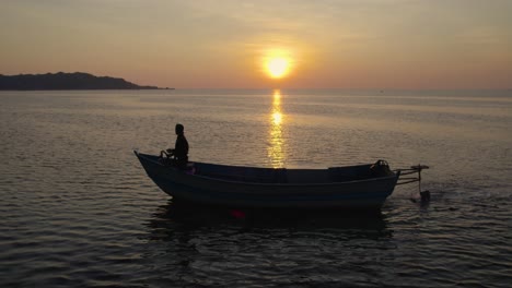 Silhouette-Eines-Fischers-In-Seinem-Boot,-Der-Während-Der-Goldenen-Stunde-Nach-Fisch-Sucht