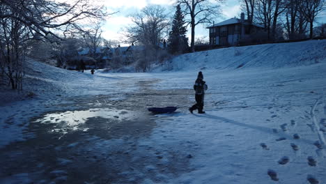 Wide-shot-of-a-young-kid-rescuing-a-toboggan-from-an-icy-patch