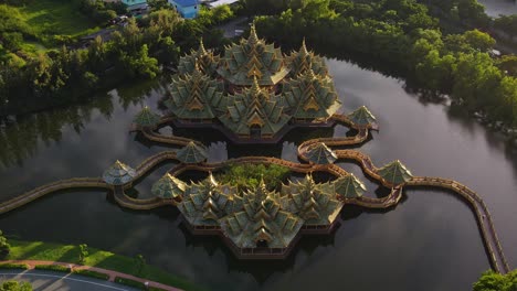 Aerial-Reveal-of-a-Green-and-Gold-Temple-on-the-water-Ancient-City-Siam,-Bangkok,-Thailand