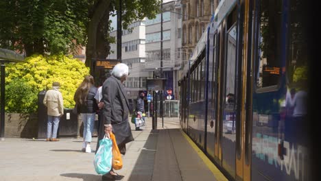 Handheld-static-shot-of-tram-pulling-up-and-people-going-to-get-on-in-Sheffield-city-centre,-England
