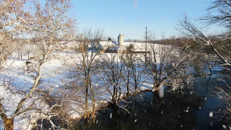 AERIAL-Lift,-Calm-River-Flowing-Through-Rural-Property-During-Snowfall