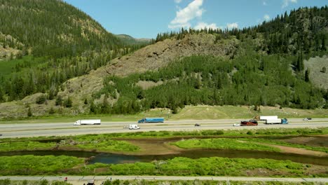 Vehicular-traffic-along-a-mountain-highway-in-the-Colorado-Rockies---aerial-tilt-up-descending-view