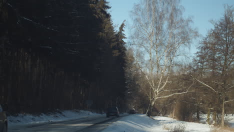 Countryside-rural-road-crossing-the-snowed-forest-near-Harasov-Lake,-Czech-Republic---Wide-static-shot