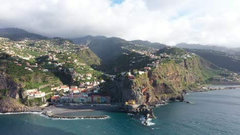Kreisende-Drohnenaufnahme,-Die-Eine-Von-Klippen-Umgebene-Kleine-Stadt-Auf-Der-Insel-Madeira-Bei-Sonnenaufgang-Zeigt