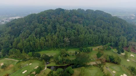 Golf-course-at-foot-of-tropical-forest-at-Tidar-hill-Magelang,-Java,-Indonesia