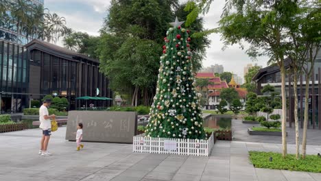 Father-and-kid-look-to-Christmas-Tree-decoration,-Balestier,-Singapore