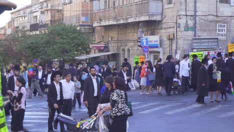 Religious-Jews-In-traditional-dress,-walk-at-a-central-intersection-in-Jerusalem,-in-Rush-hour-time