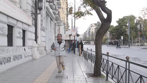 Man-running-through-the-streets-of-Athens,-Greece